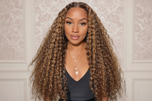 Woman with long, wavy hair wearing a black top against a neutral wall. 100% Unprocessed Brazilian Human Lace Front Wig Blonde Highlights 13x6 HD Deep Wave Glueless Lace Frontal Wigs