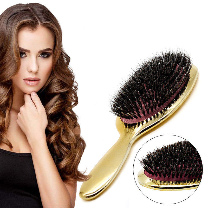 Woman with long, glossy curled brunette hair beside a gold wild boar bristle air cushion paddle hair brush featuring dense black bristles, cushioned base and ergonomic handle for detangling, smoothing, frizz control, scalp massage and everyday hair care.
