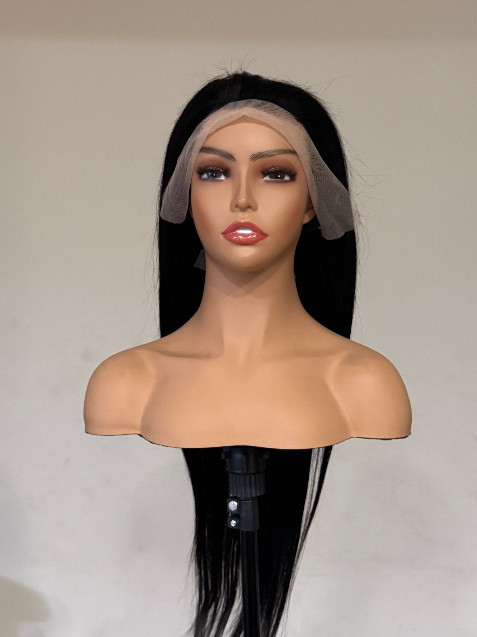 Mannequin head with a black wig and a clear mesh cap on a plain background brazilian straight wig, brazilian straight lace front wig, straight lace front wig, straight human hair wig, natural black wig, black lace front wig, human hair wig, 100% human hair wig, glueless wig, ready to wear wig, natural hairline wig, realistic lace front wig, premium human hair wig, luxury wig, long straight wig, long black wig, heat safe wig, everyday wig, date night wig, photo ready wig