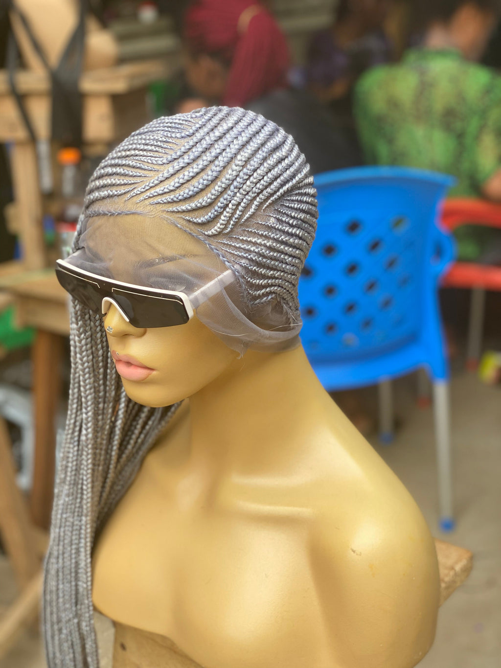 Mannequin head with a silver braided wig and sunglasses in an indoor setting. cornrow braid wig, cornrow braided wig, glueless braided wig, glueless lace wig, HD lace braided wig, HD lace wig, full lace braided wig, full lace wig, human hair braided wig, human hair wig, braided wig, braided wig, glueless lace wig, lemonade braid wig, lemonade braids wig, side part braided wig, side part wig, hand braided wig, handmade braided wig, handcrafted wig, premium braided wig, luxury braided wig, luxur