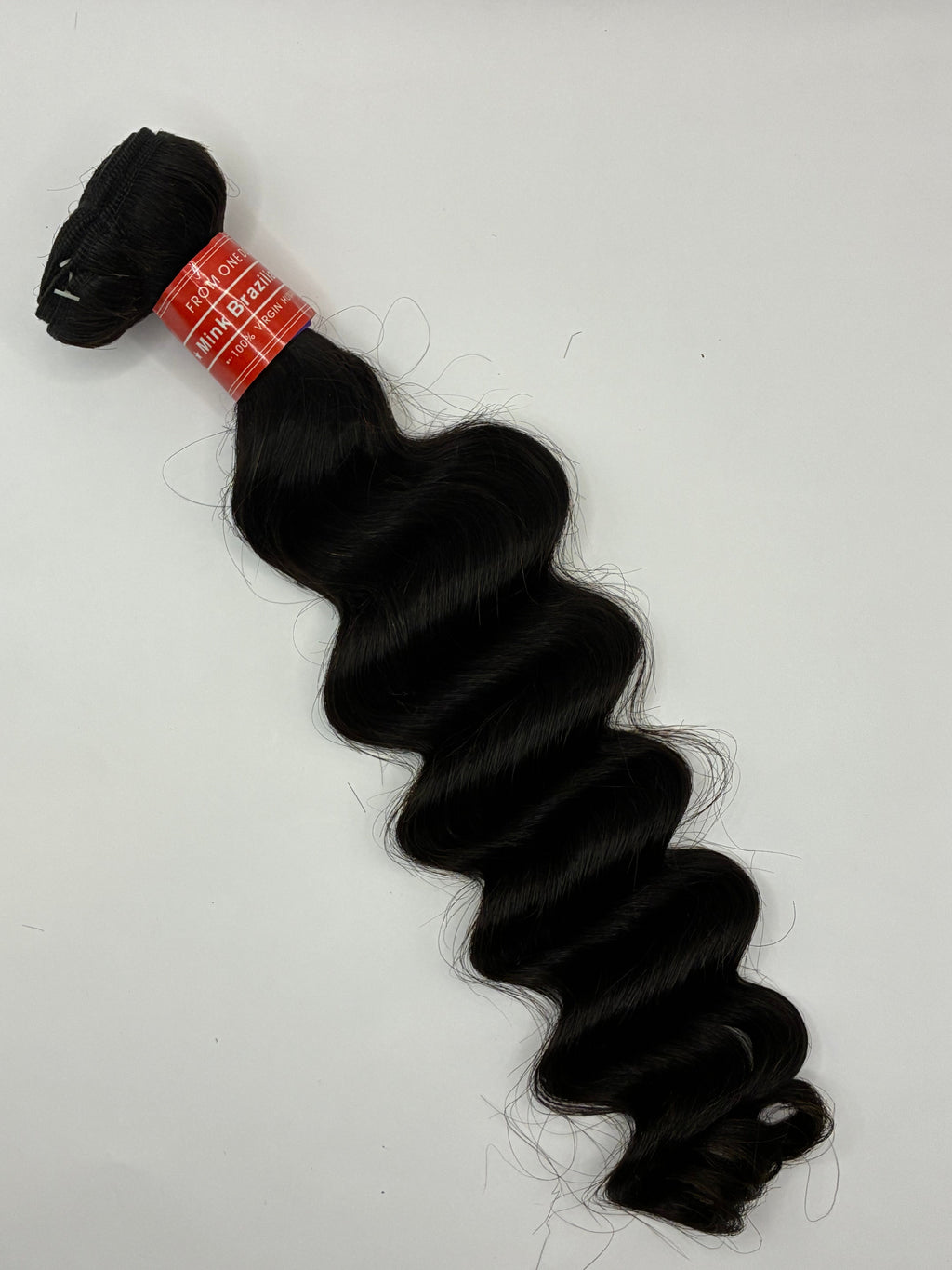 Black hair bundle with a red label on a white background Shop premium Loose Deep Virgin Human Hair Bundles in Natural Black. Soft, bouncy waves, minimal shedding, natural luster, and long-lasting luxury quality for sew-ins, wigs, and protective styles. Crown'd Cuties Loose Deep Virgin Human Hair Bundle in Natural Black featuring soft, voluminous loose deep waves with natural luster and healthy shine.