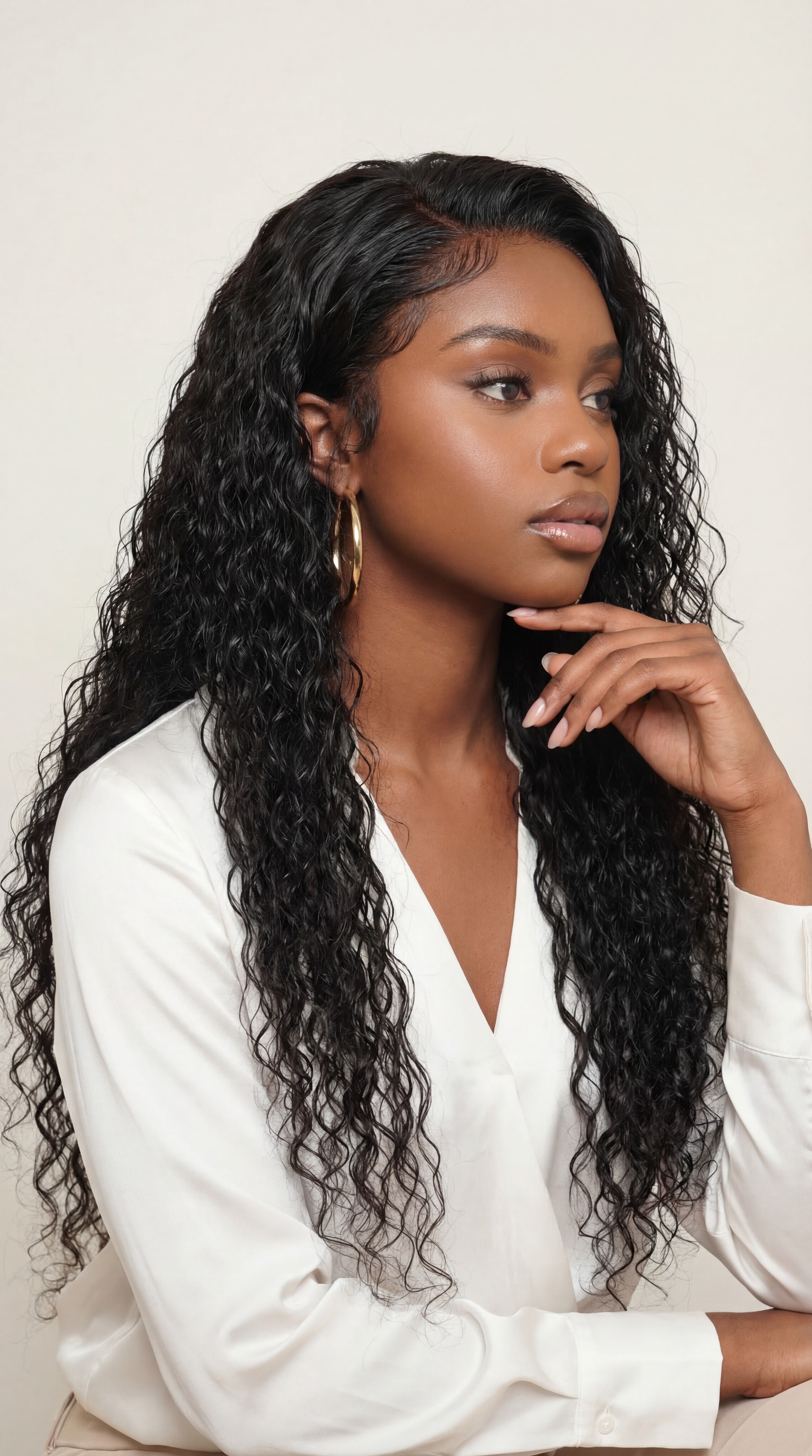 Woman with long, wavy hair wearing a white blouse against a plain background