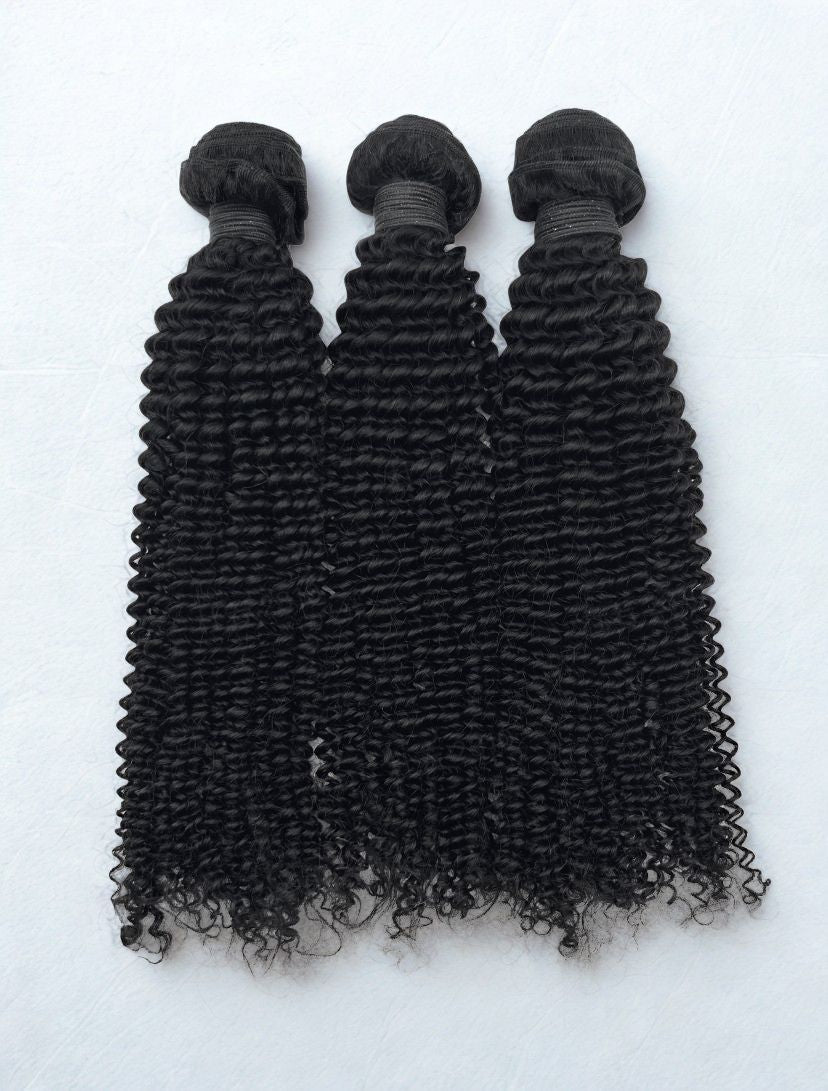 Three bundles of curly black hair extensions on a white background