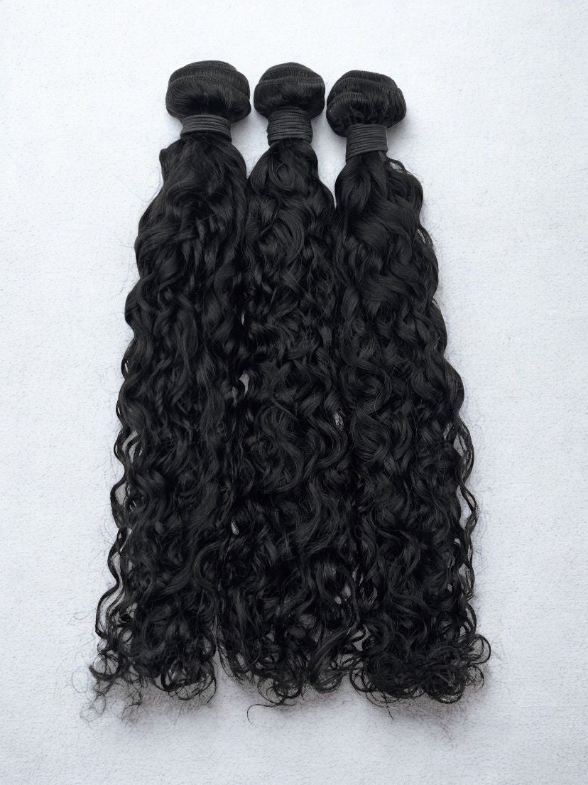 Three bundles of curly black hair extensions on a white background Natural Wave Wefted 1B Natural Black Hair Bundle 100% Human Hair Bundles - 18” to 26”