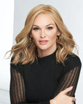 Woman with blonde hair wearing a black top with a striped sleeve on a white background