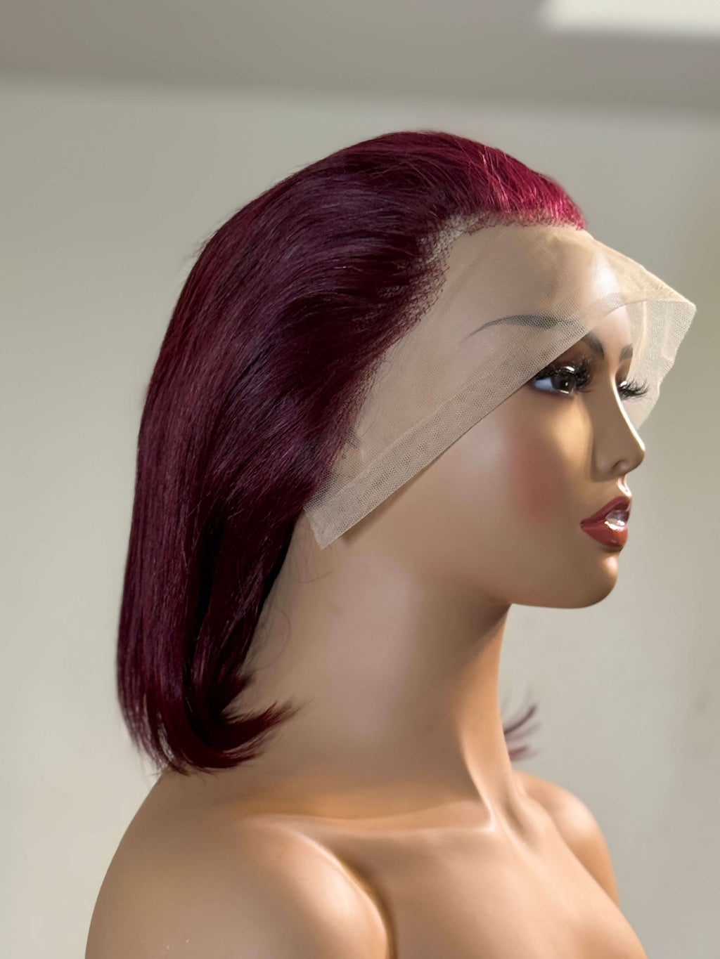 Mannequin head with a burgundy wig and clear visor on a plain background burgundy wig, burgundy red wig, burgundy lace front wig, burgundy human hair wig, wine red wig, wine color wig, red lace front wig, red human hair wig, red bob wig, burgundy bob wig, burgundy lace wig, burgundy human hair bob wig, straight bob wig, straight lace front wig, straight human hair wig, human hair bob wig, lace front bob wig, bob lace wig, chic bob wig, sleek bob wig, short human hair wig, short lace front wig, short bob wig