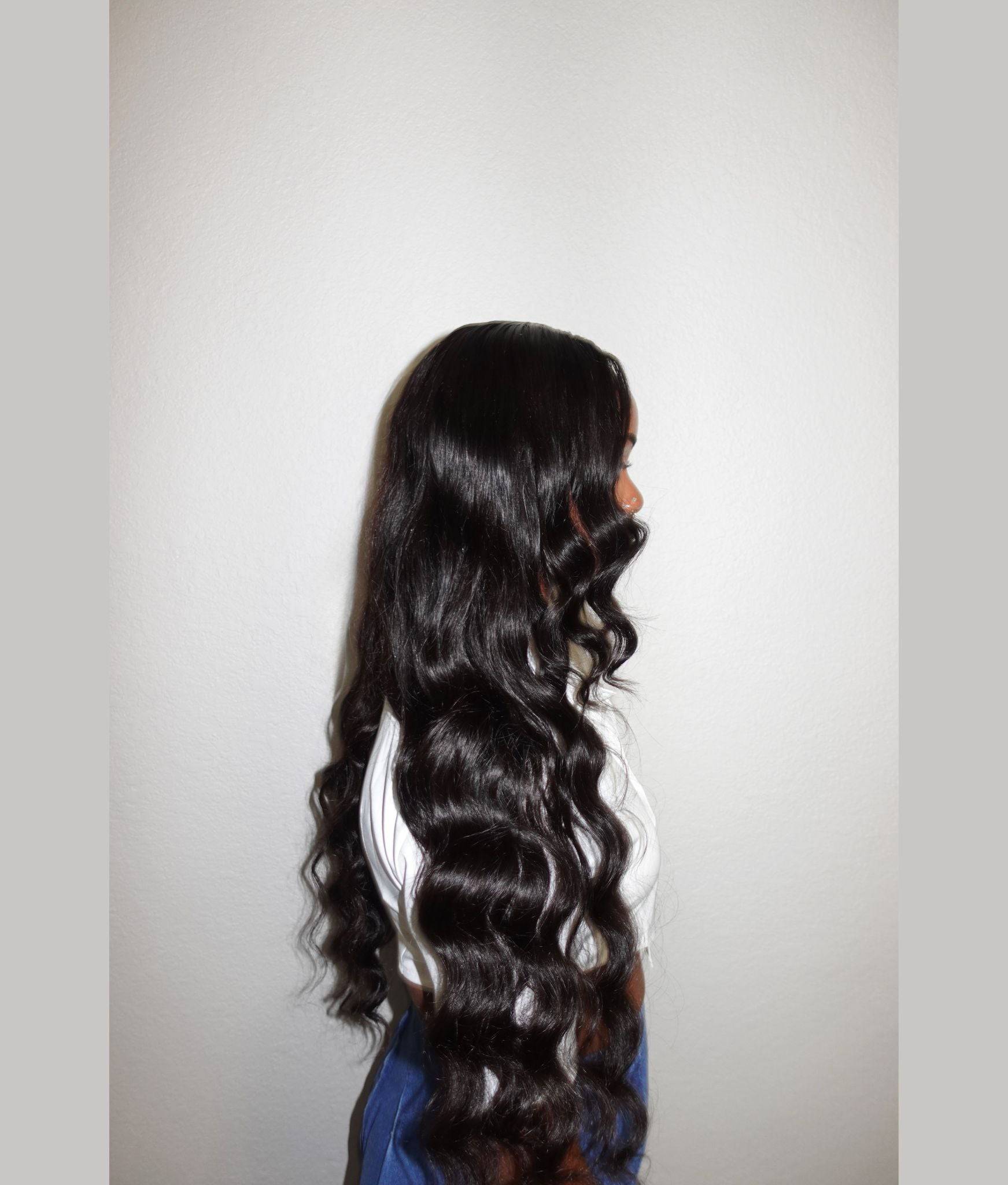 Person with long, wavy black hair on a plain background Body Wave 100% Virgin Human Hair – No tangles, no shedding, all softness. 16”–30”