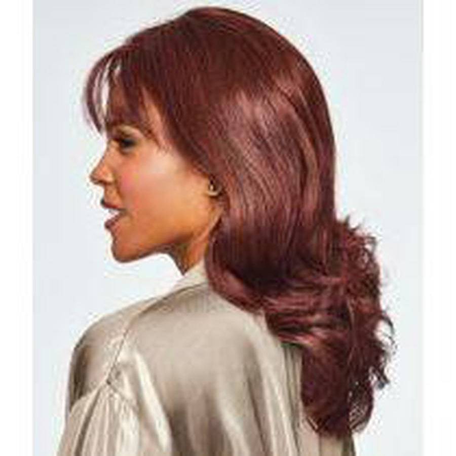 A woman shown in side profile wearing a shoulder-length, wavy wig with deep reddish-brown color and a light-colored satin blouse against a plain light gray background.