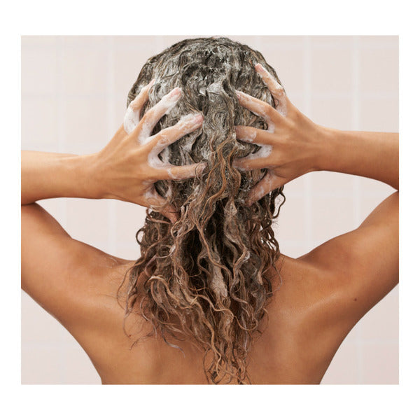 Person washing blonde highlighted hair with L’Oréal sulfate-free blonde shampoo with iris for brightening hair care
