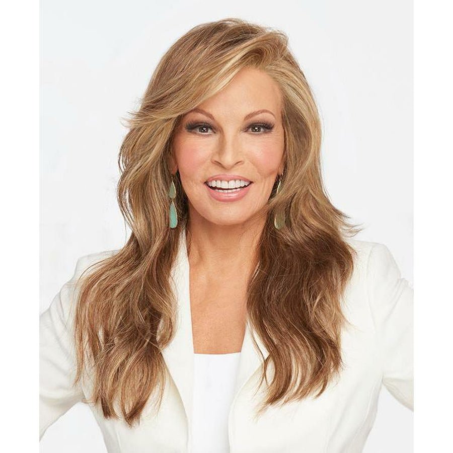 A smiling woman with long, wavy blonde-brown hair wearing a white top, shown from the chest up against a light gray studio background. Miles of Style - Wig by Raquel Welch