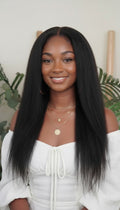 Woman with long straight black hair wearing a white off-shoulder top indoors.