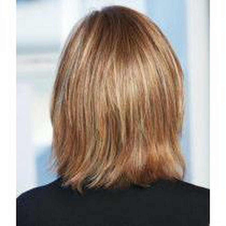 A person shown from the back wearing a shoulder-length layered wig with warm blonde and light brown highlights, against a softly blurred light background.