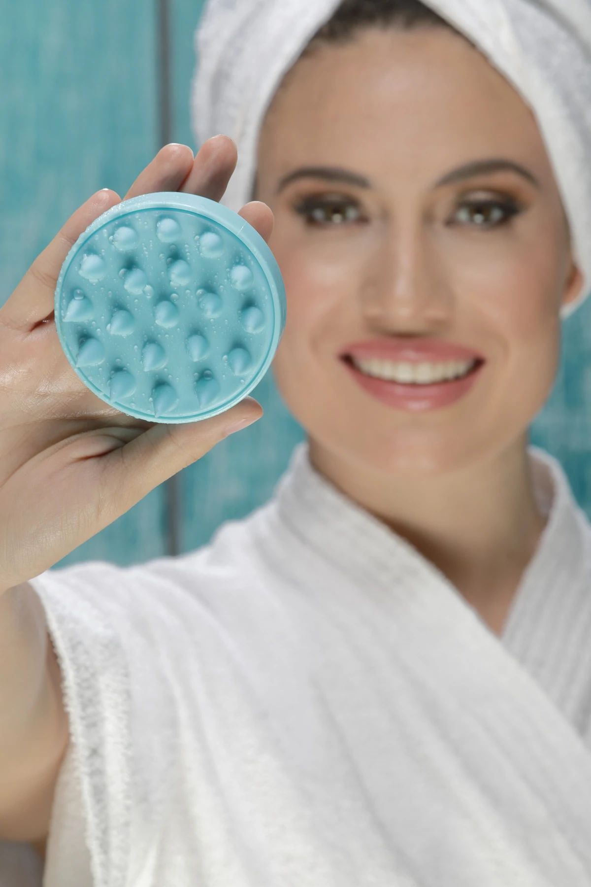 Woman holding a blue silicone scalp massager brush with soft rounded bristles for deep cleansing, exfoliating and shampoo scalp care.