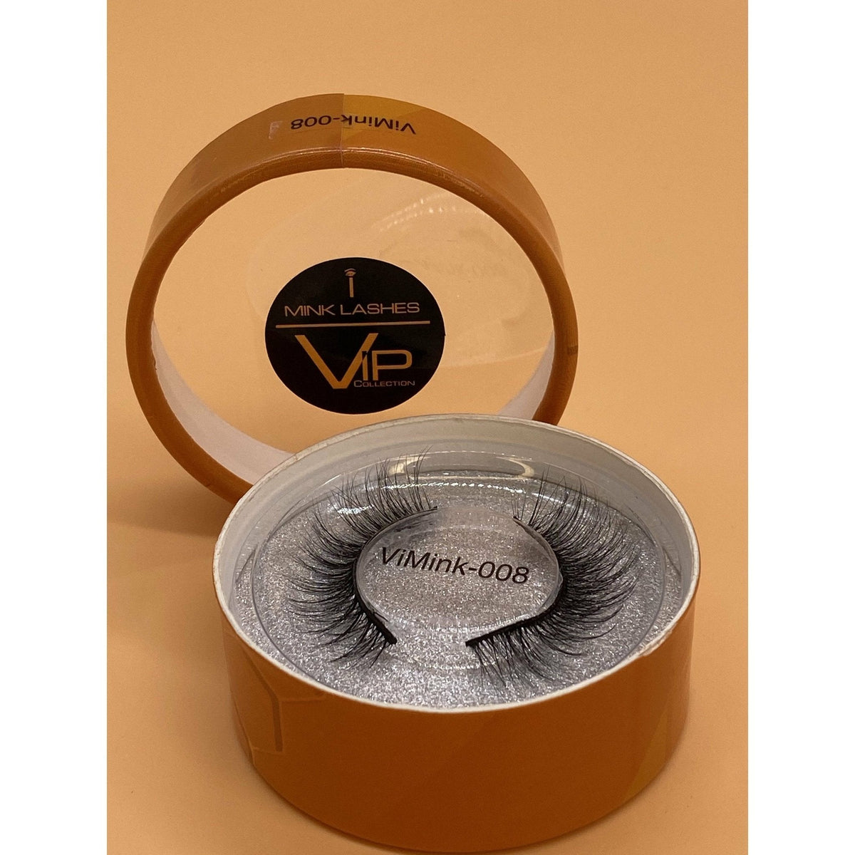 Mink eyelashes in a brown container with VIP branding on a beige background