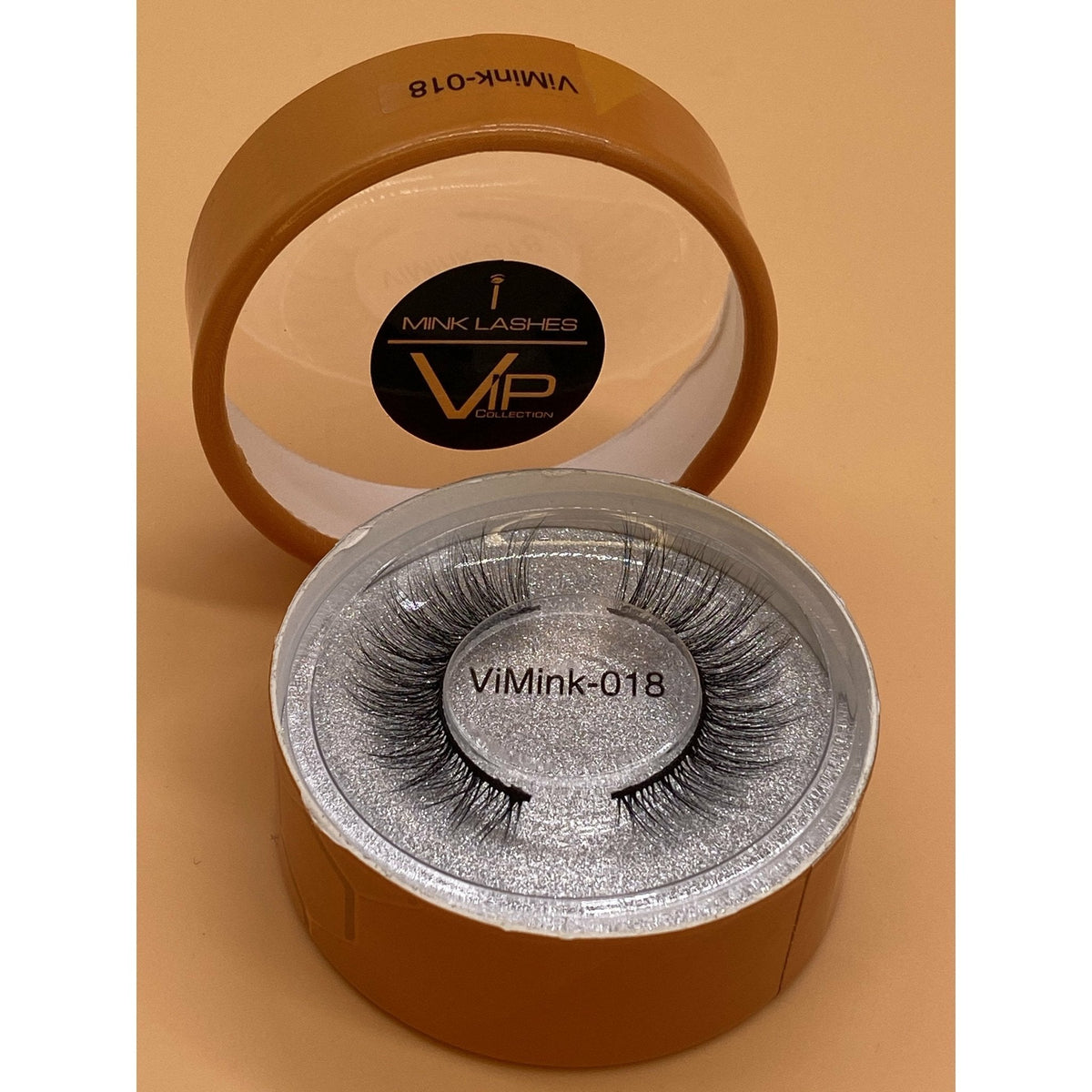 Mink lashes in a round container with visible branding on a beige background