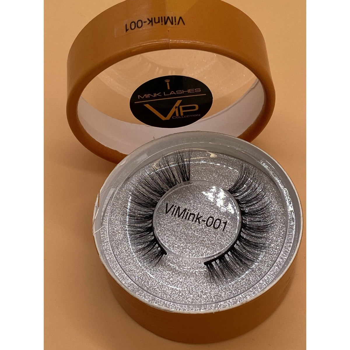 Mink eyelashes in a container with 'VIMINK' branding on a beige background