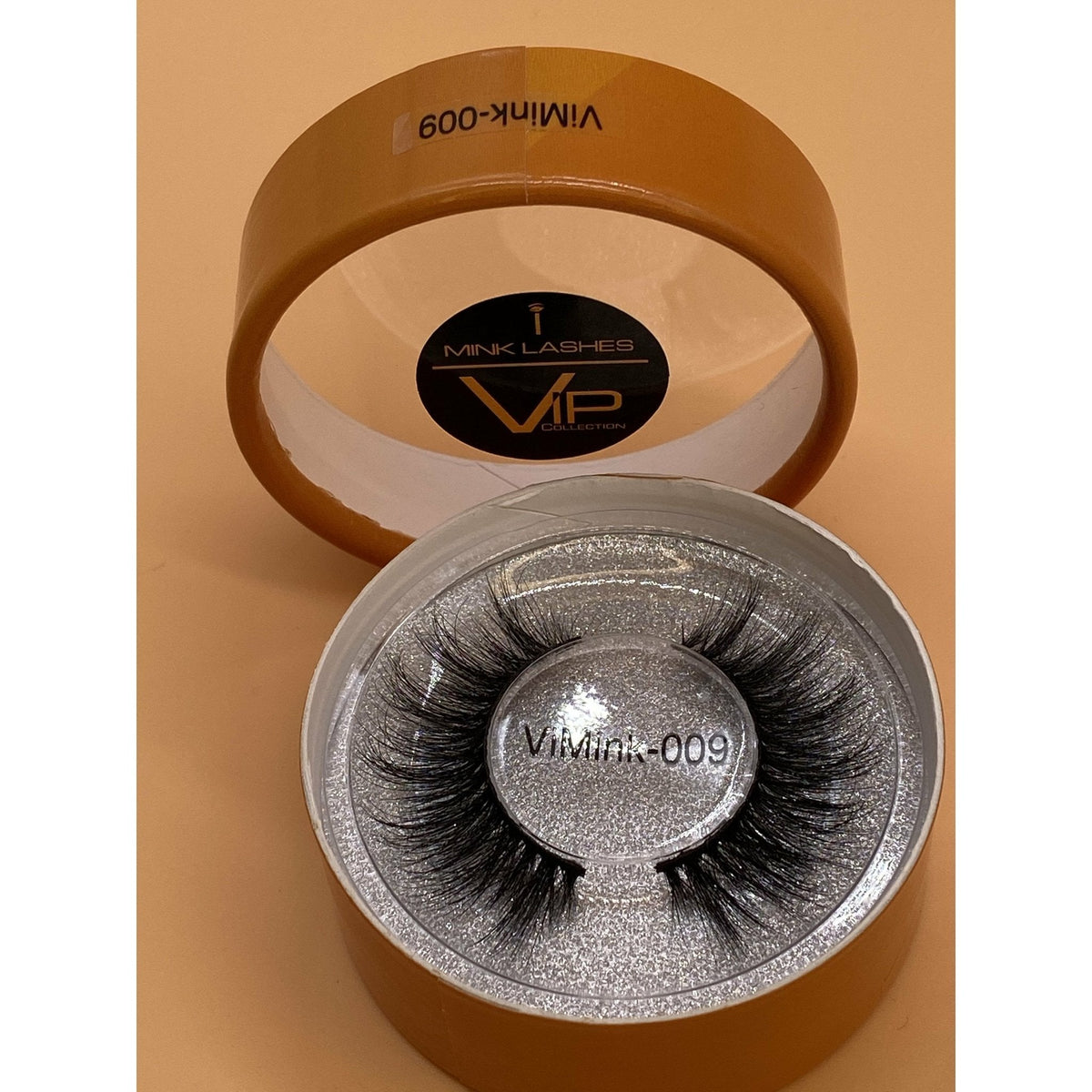 False eyelashes in a branded container on a beige background